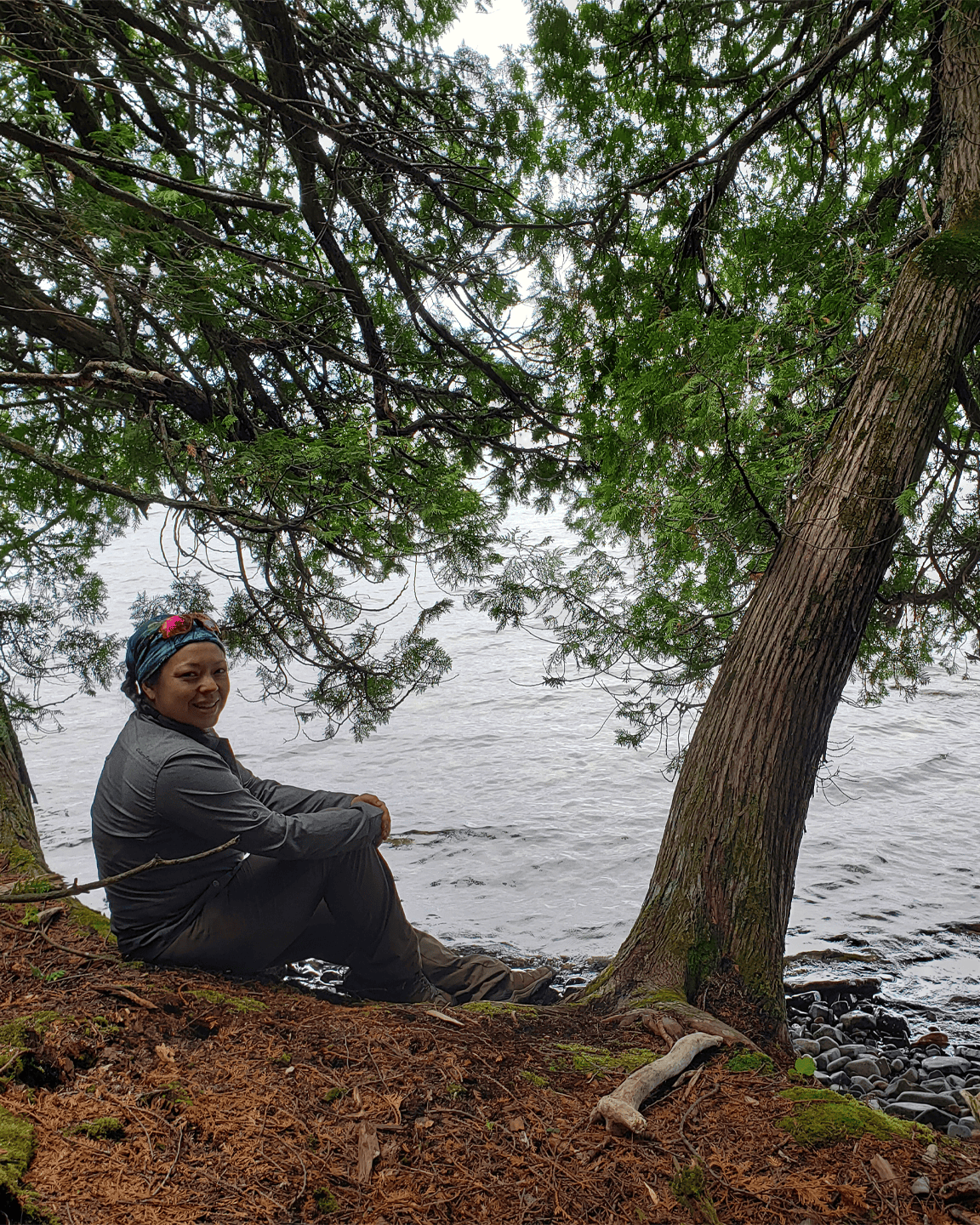 Naomi Fong sitting along the shore of a lake in between two trees. Self reflection. How it can feel being in a relationship with an avoidant